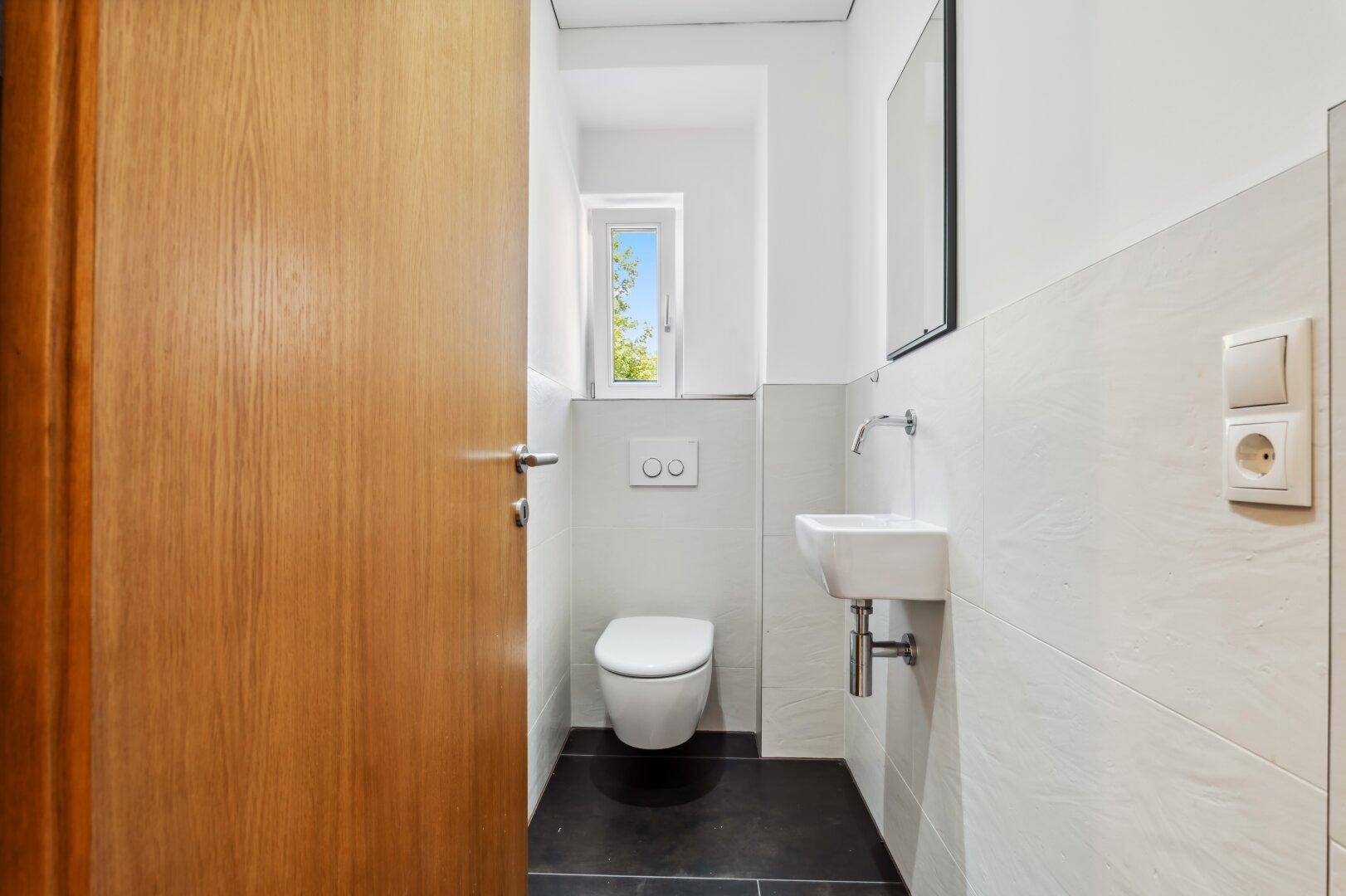Modernes Gäste-WC mit wandhängendem WC, kleinem Waschbecken und Fenster.