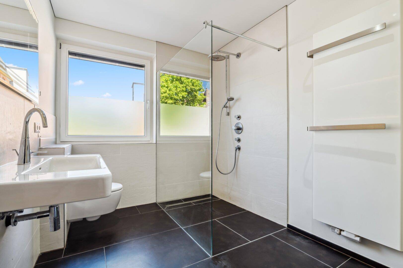 Modernes Badezimmer mit ebenerdiger Dusche, großem Waschbecken und Fenster.