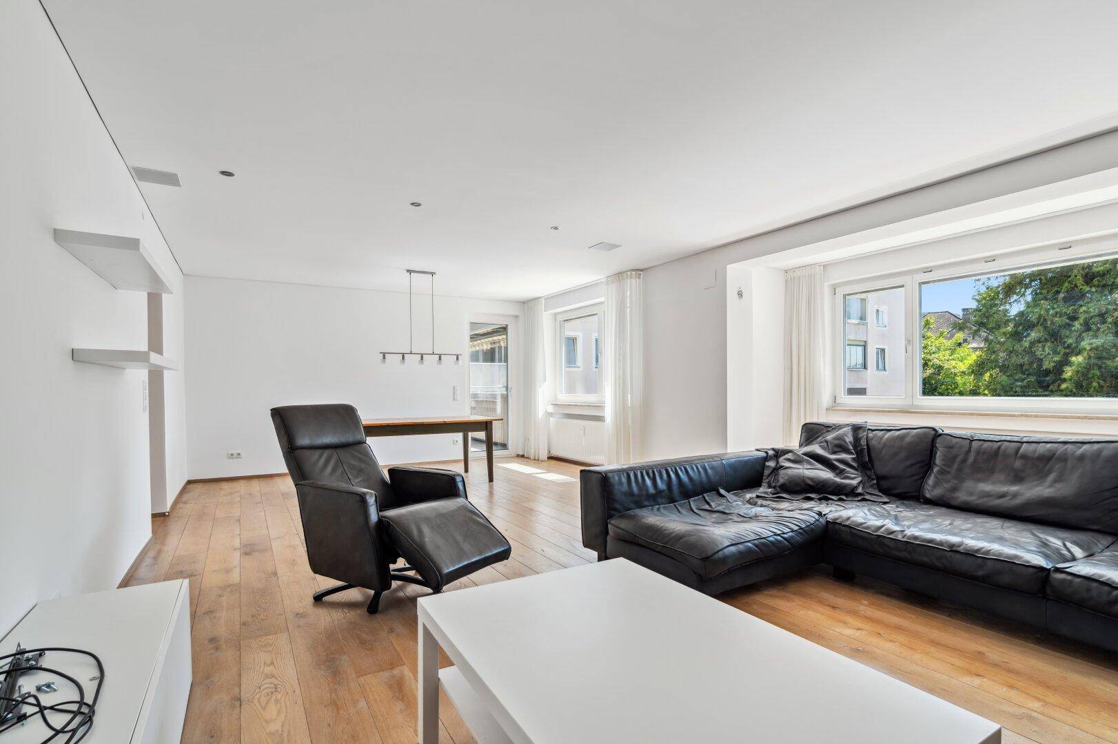 Geräumiger Wohnbereich mit Ledersofa, Sessel und Blick auf die Umgebung.