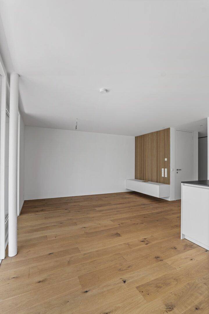 Heller Wohnbereich mit Holzboden, weiß gestrichenen Wänden und dekorativer Holzverkleidung.