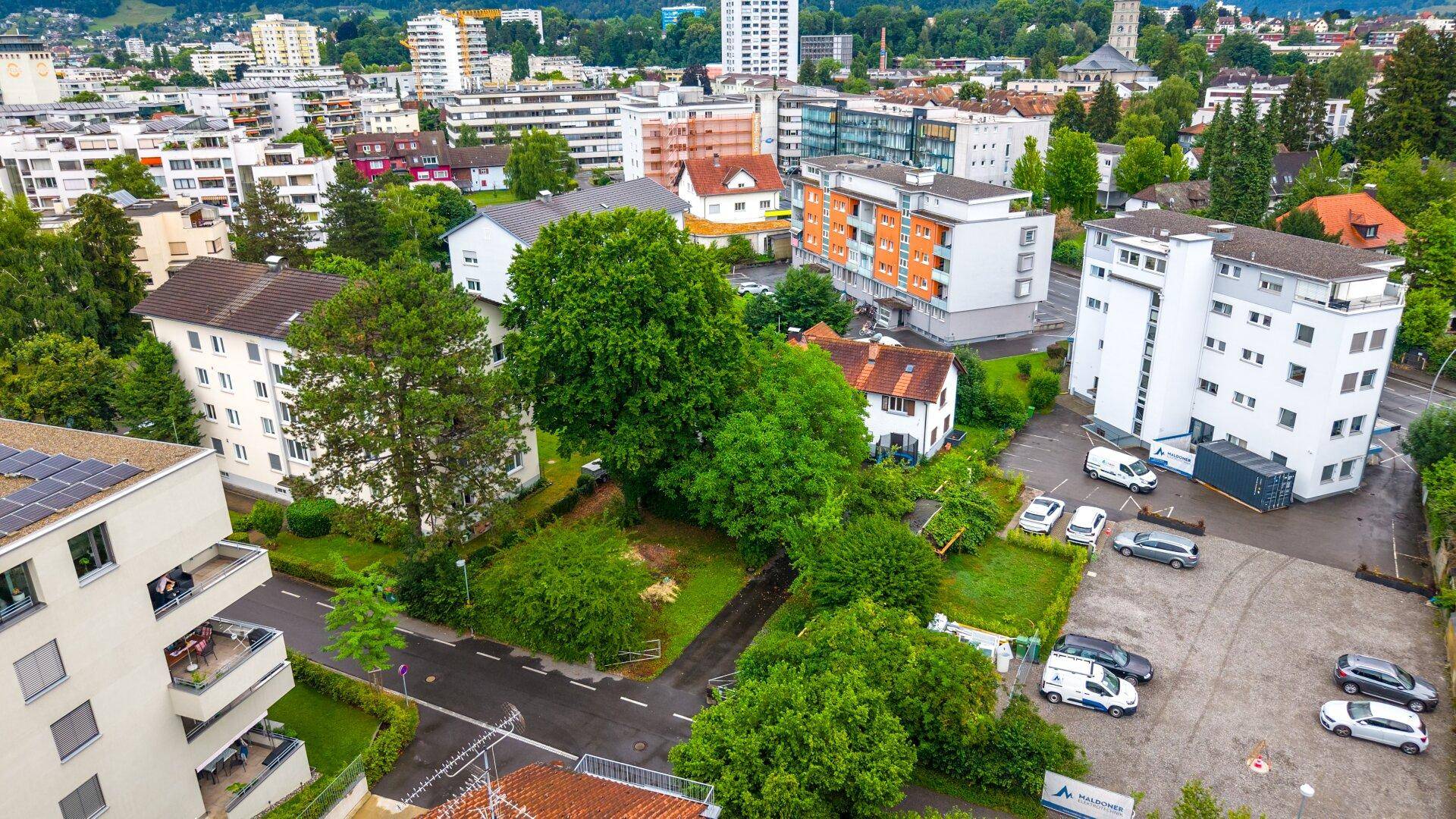Panoramische Luftaufnahme einer städtischen Wohngegend mit vielfältiger Bebauung und viel Grünfläche.
