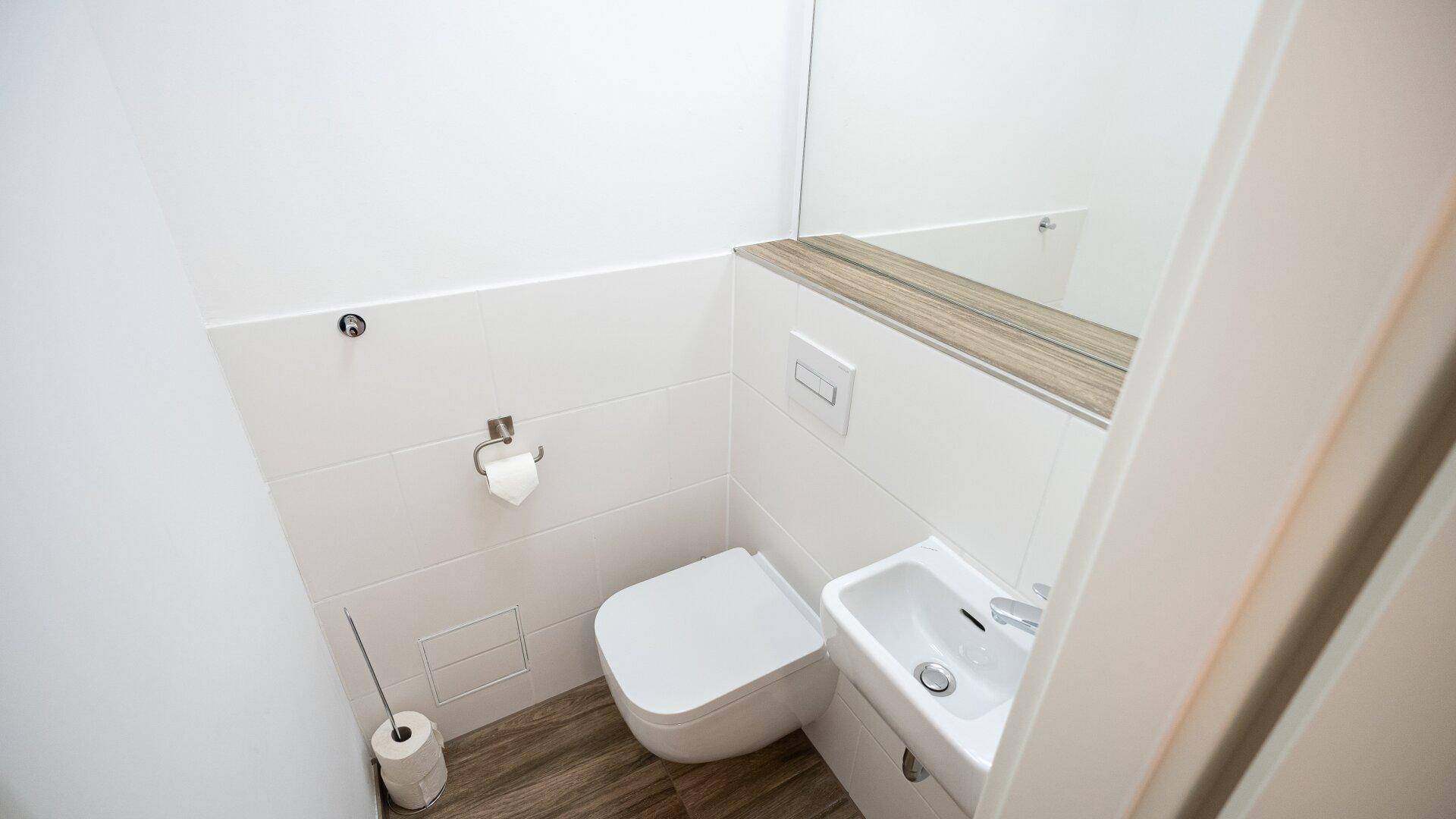 Kleines Gäste-WC mit wandhängender Toilette und Handwaschbecken.