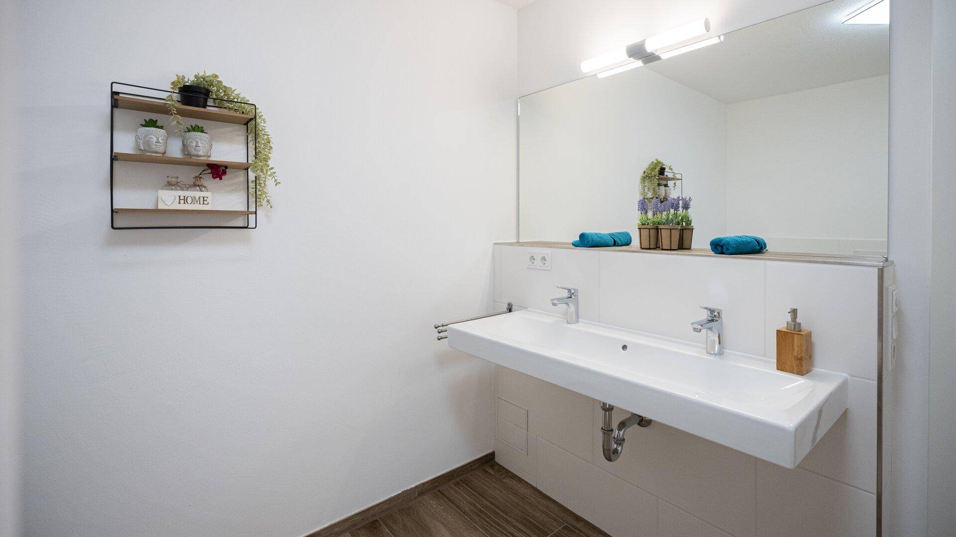 Modernes Badezimmer mit Doppelwaschbecken und großem Spiegel, hell und funktional.