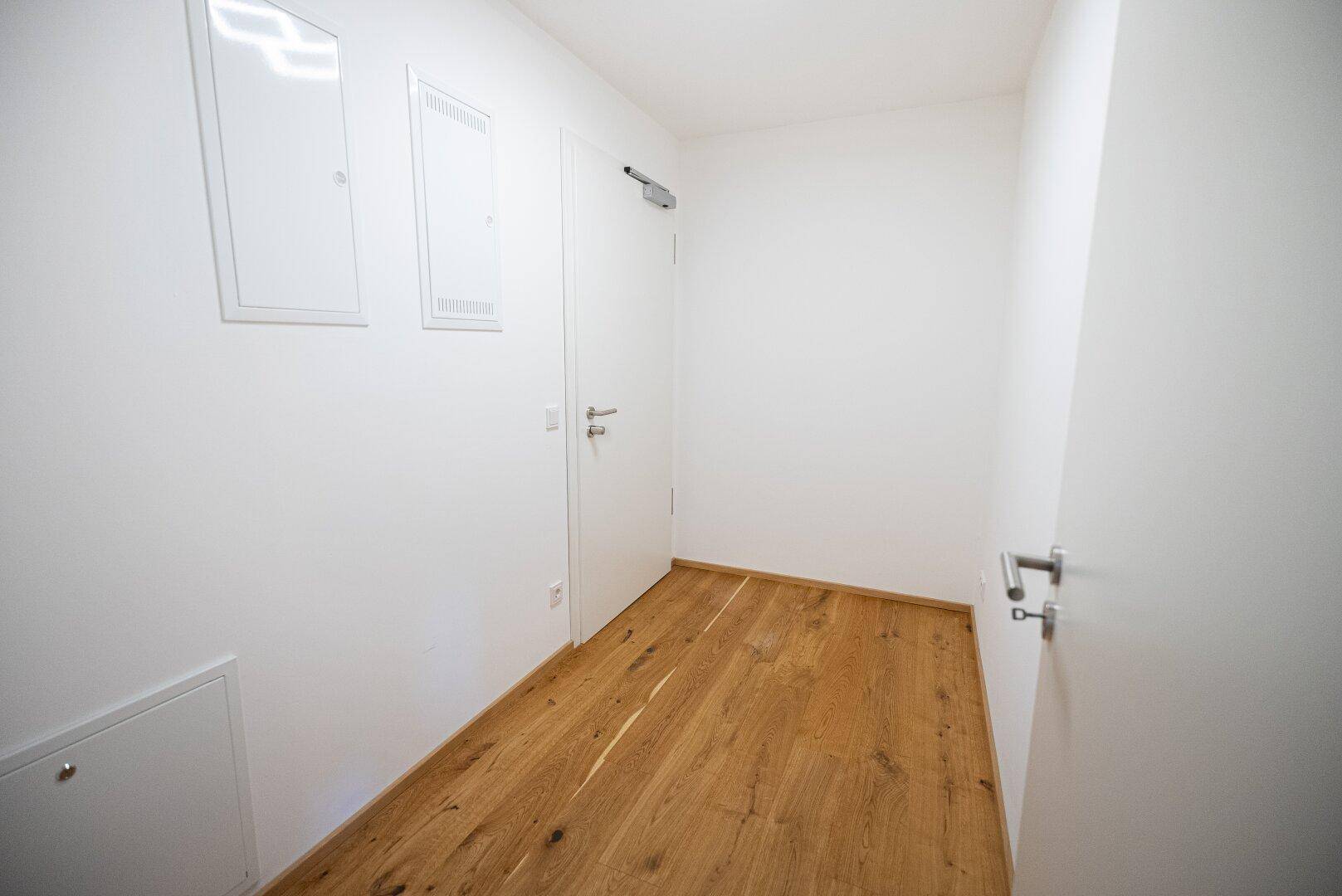 Langer, heller Flur mit Holzboden und mehreren Türen zu den Zimmern.