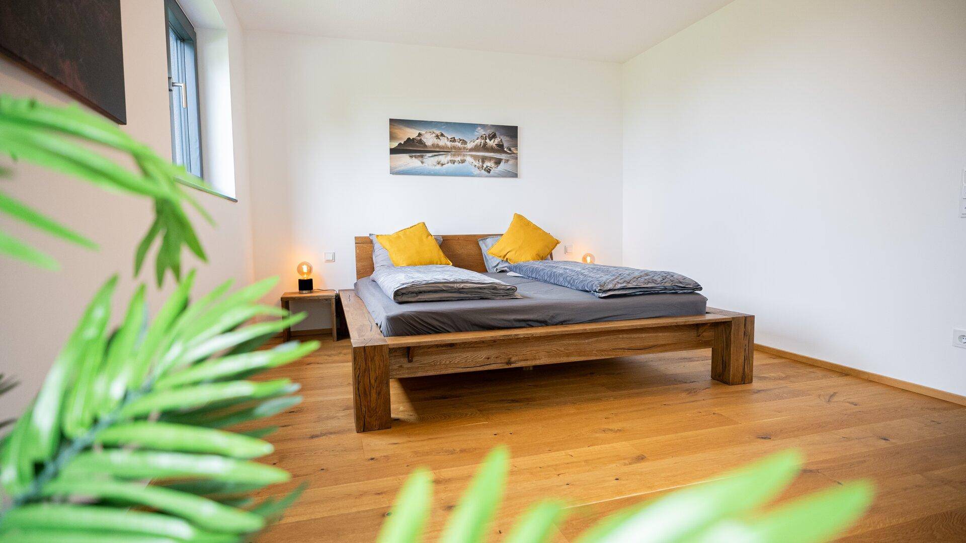 Gemütliches Schlafzimmer mit Holzbett und Nachttischen, gut beleuchtet.