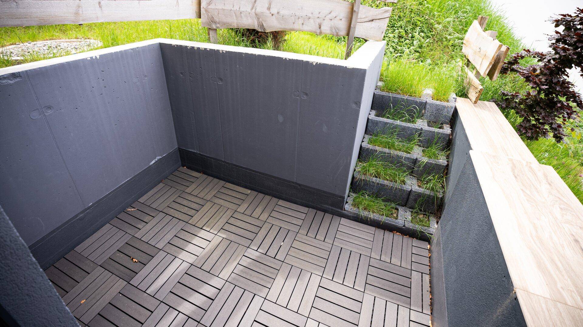 Kleine, geflieste Terrasse im Untergeschoss mit Treppenzugang zum Garten.