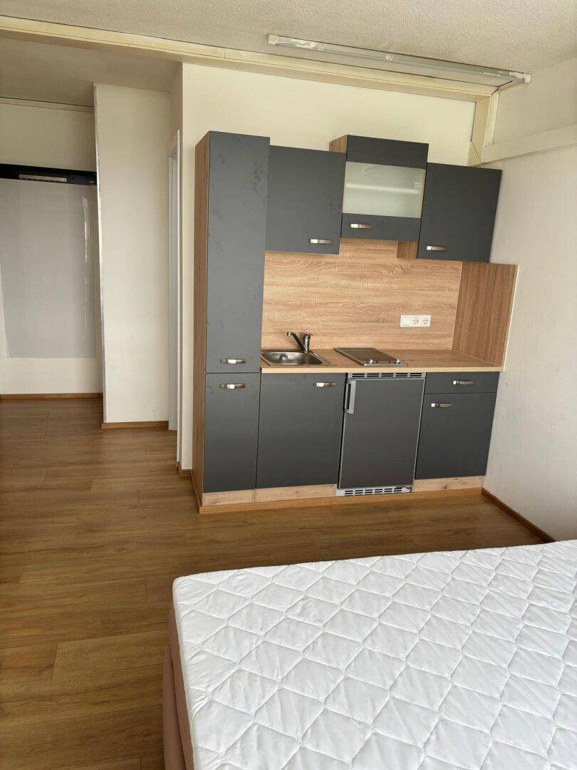 Schlafzimmer mit integrierter moderner Küchenzeile und Laminatboden.