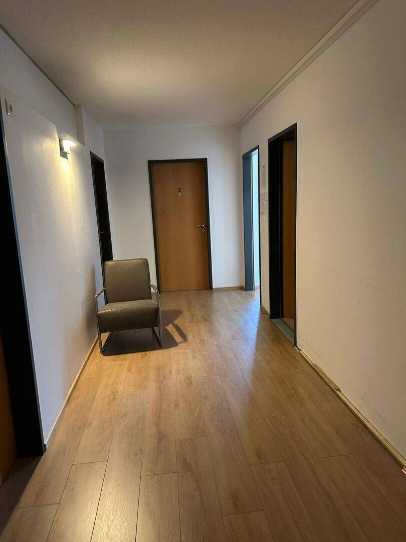Geräumiger Flur mit Laminatboden und einem Sessel als Sitzgelegenheit.