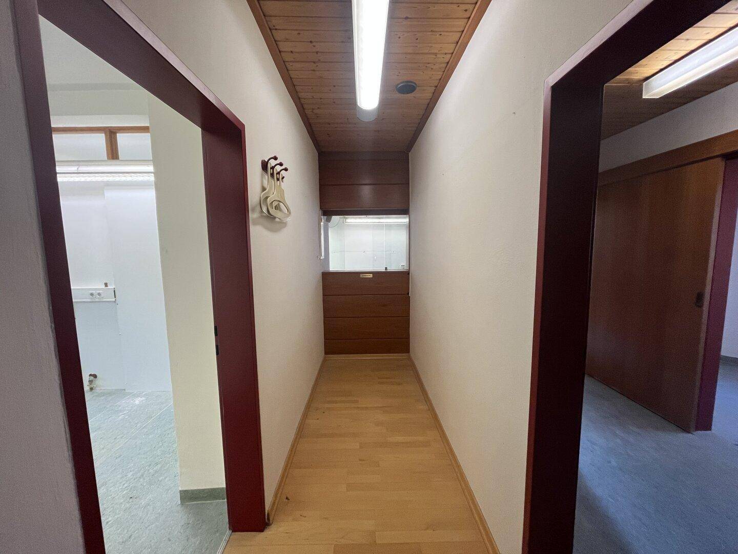 Langer Flur mit Holzdecke und Holzboden, führt zu weiteren Räumen und einem Einbauschrank.