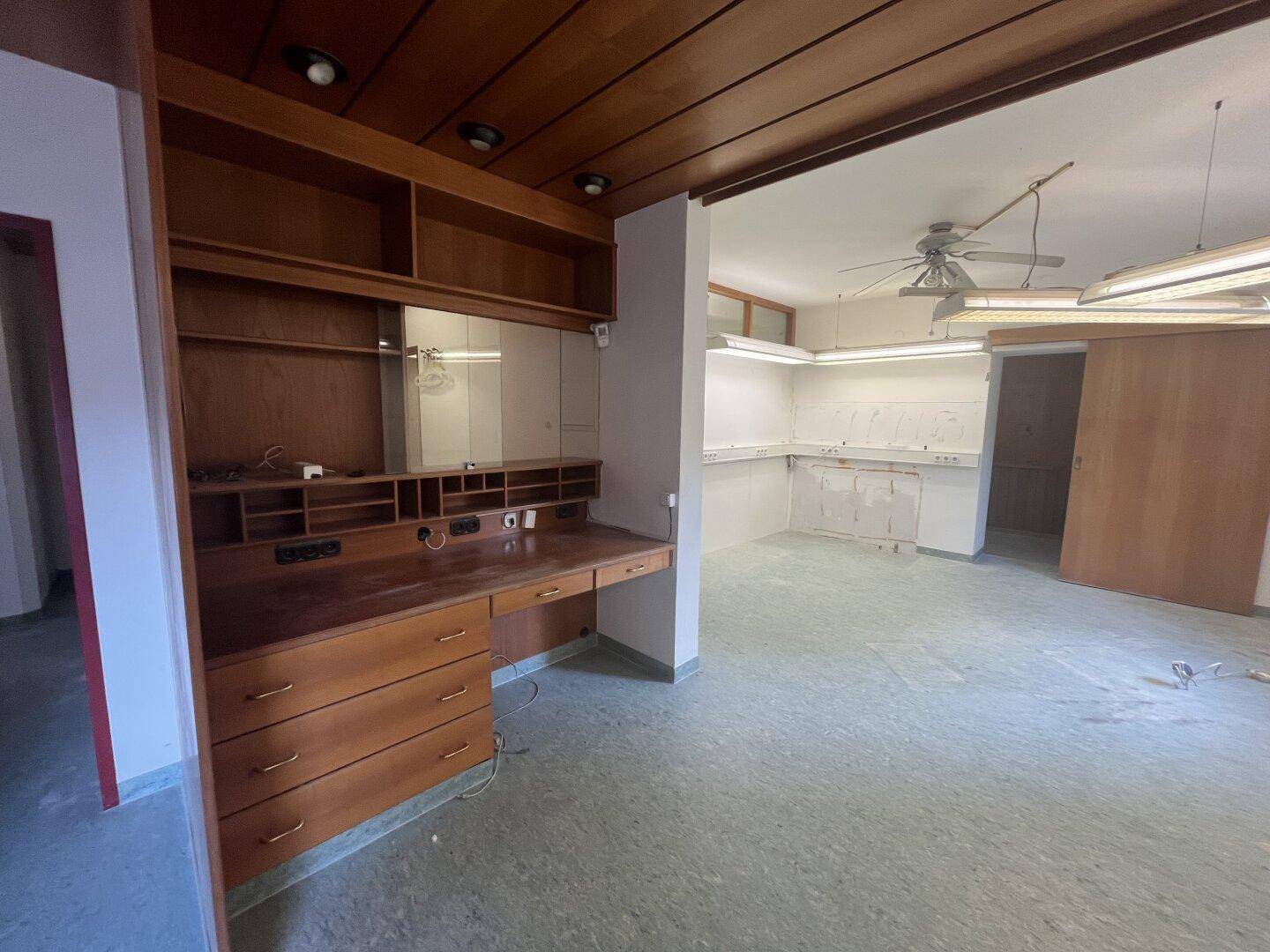 Großer Büroraum mit Holzdecke, Einbauschreibtisch und Arbeitsbereichen, ideal für gewerbliche Nutzung.