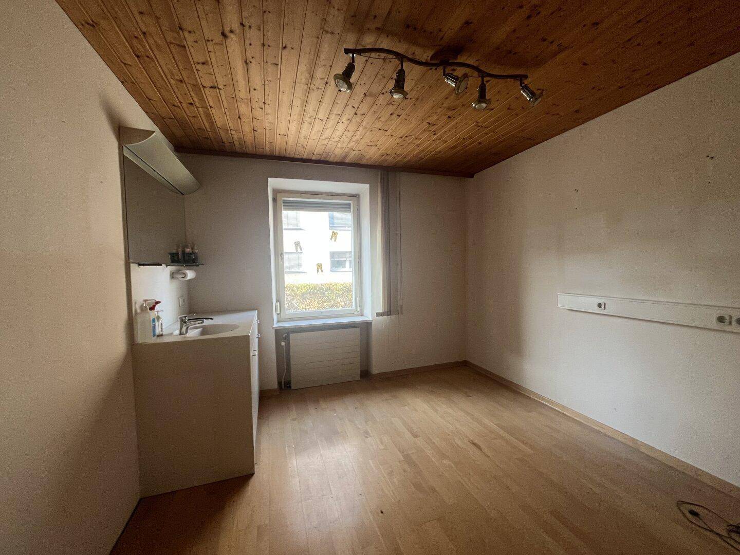 Kleiner Raum mit Holzdecke, Fenster und einem Waschbeckenunterschrank, ideal als Vorbereitungsraum.