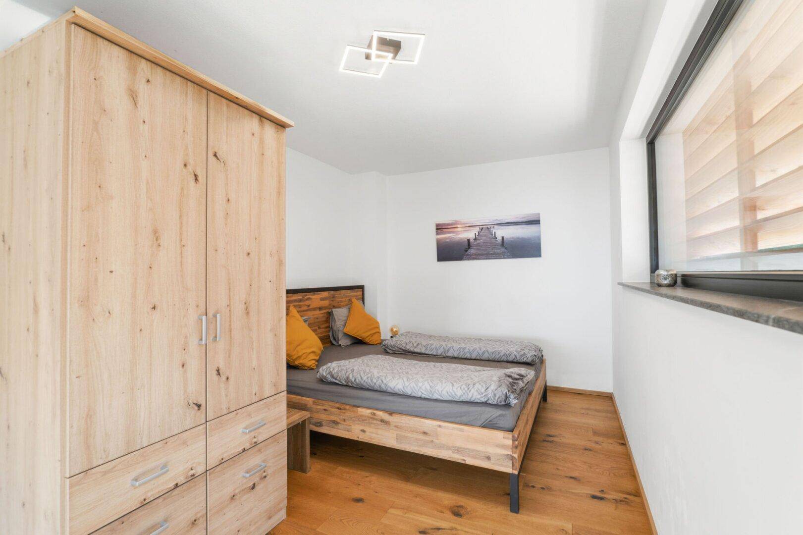 Gemütliches Schlafzimmer mit Holzbett, passendem Kleiderschrank und natürlichem Lichteinfall.