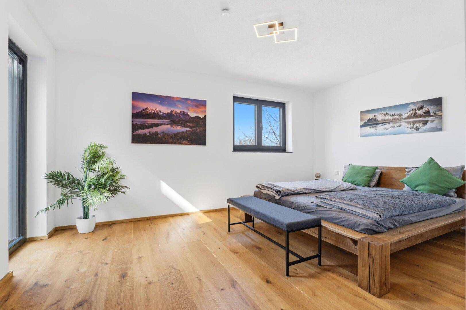 Helles Schlafzimmer mit Holzbett, großem Fenster und Zugang zum Außenbereich.