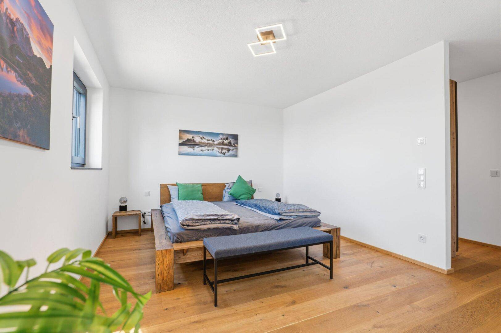 Gemütliches Schlafzimmer mit Holzbett, Holzboden und moderner Deckenleuchte.