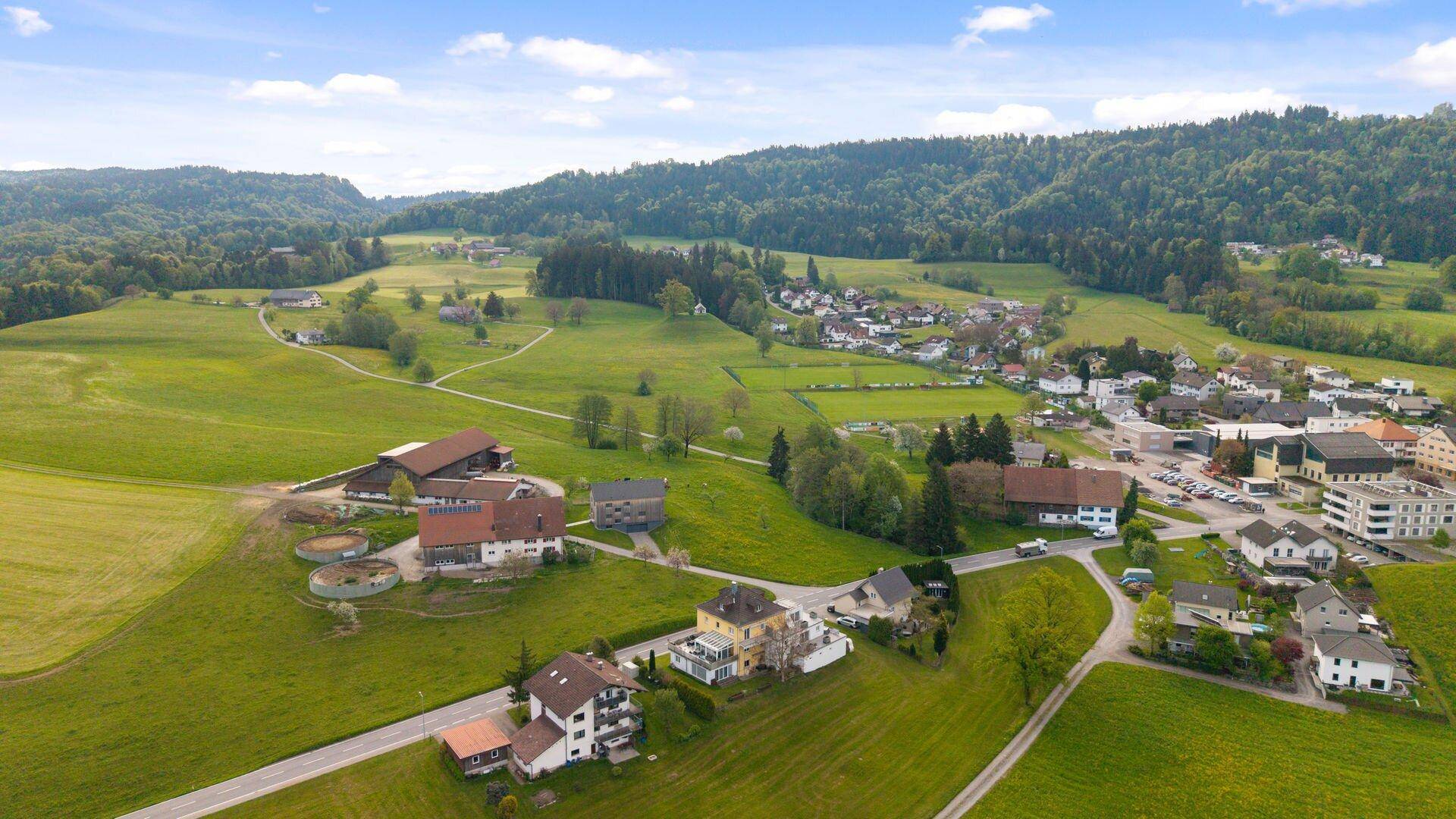 Weitläufige Luftaufnahme der ländlichen Umgebung mit Häusern und grünen Feldern.