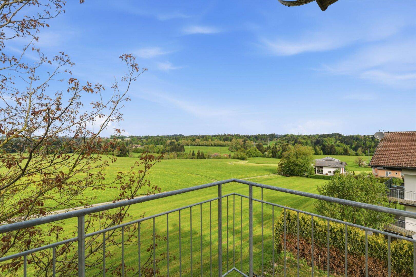 Balkon mit weitem Blick über grüne Felder und die umliegende Landschaft.