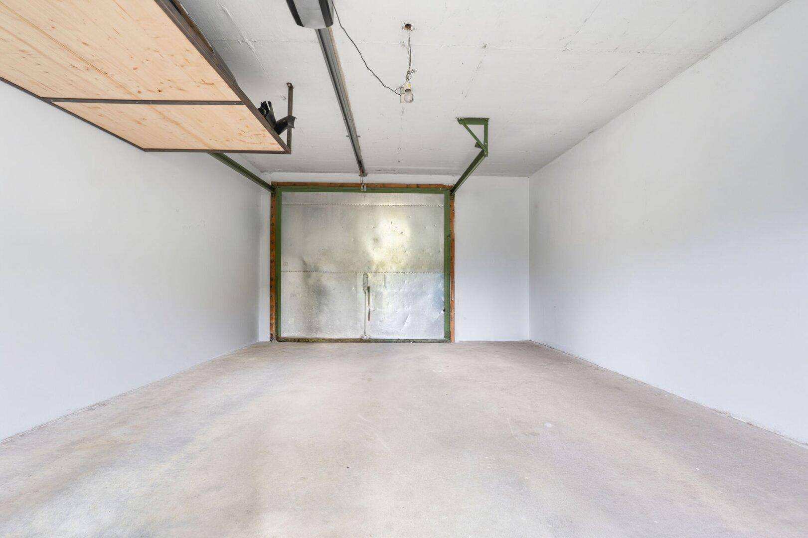 Leere Garage mit Betonboden und Metalltor.