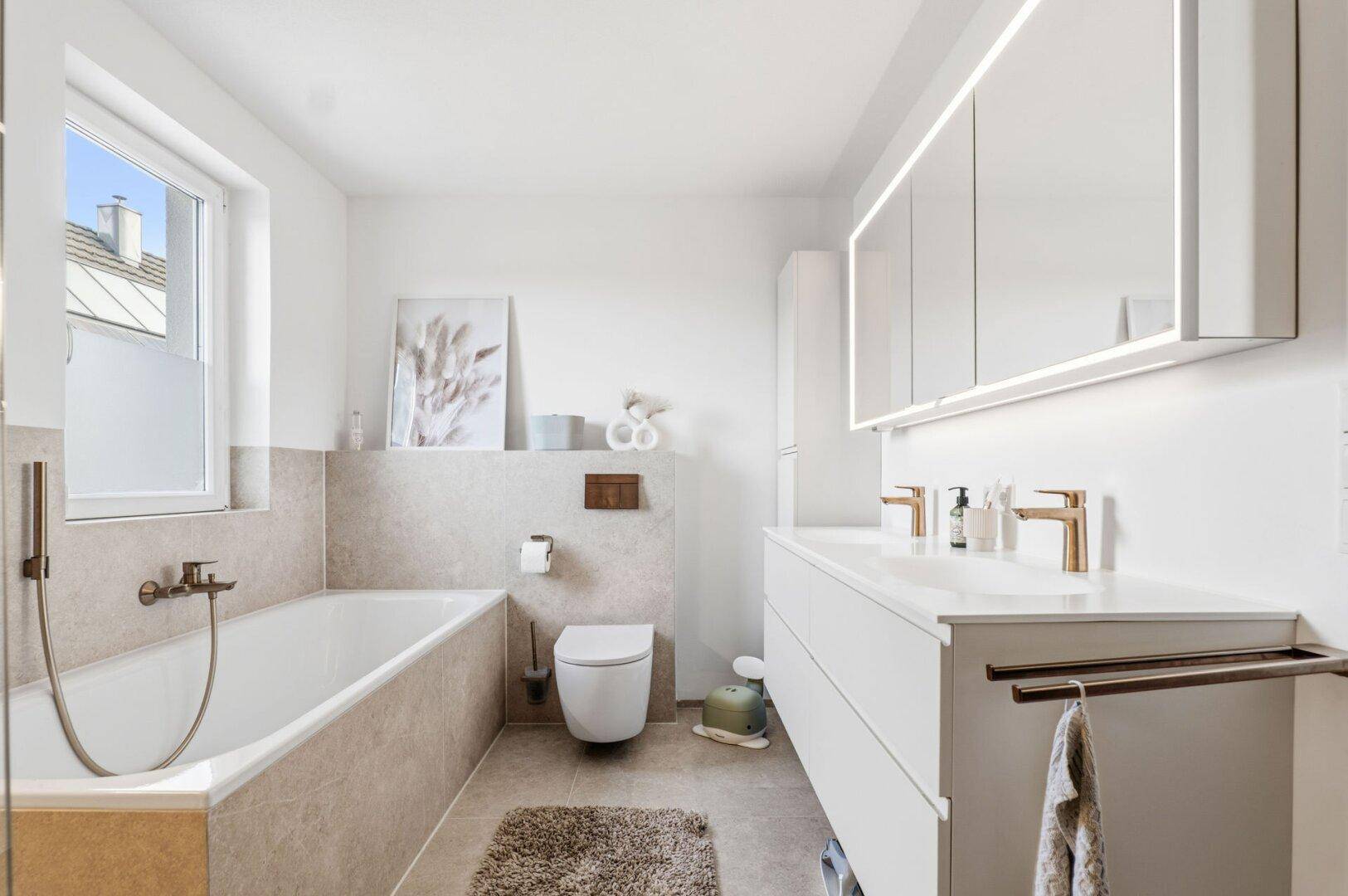 Modernes Badezimmer mit Badewanne, Doppelwaschbecken und großem Spiegelschrank.