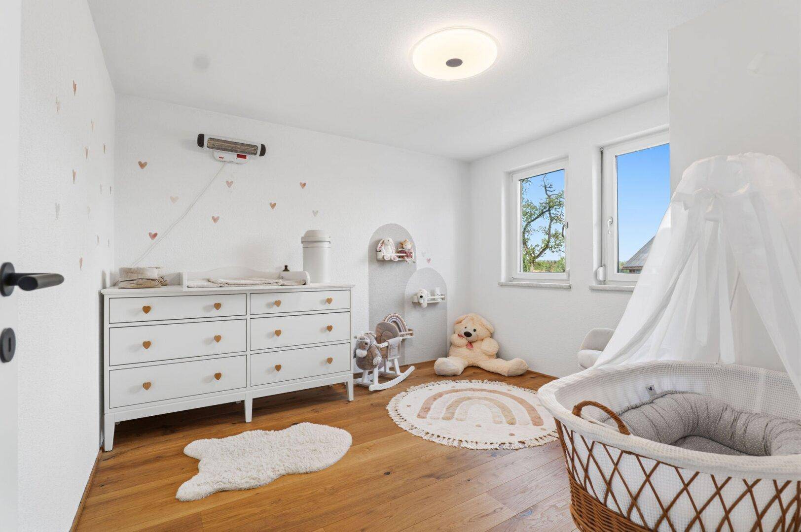 Helles Kinderzimmer mit Holzboden, Wickelkommode und Babybett.