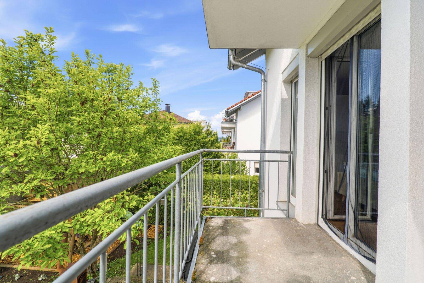 Kleiner Balkon mit Metallgeländer und Blick ins Grüne.