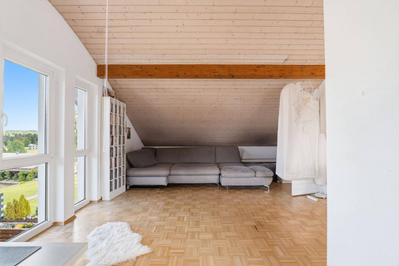 Gemütlicher Wohnbereich im Dachgeschoss mit Sofa, Holzboden und Schrägdach.