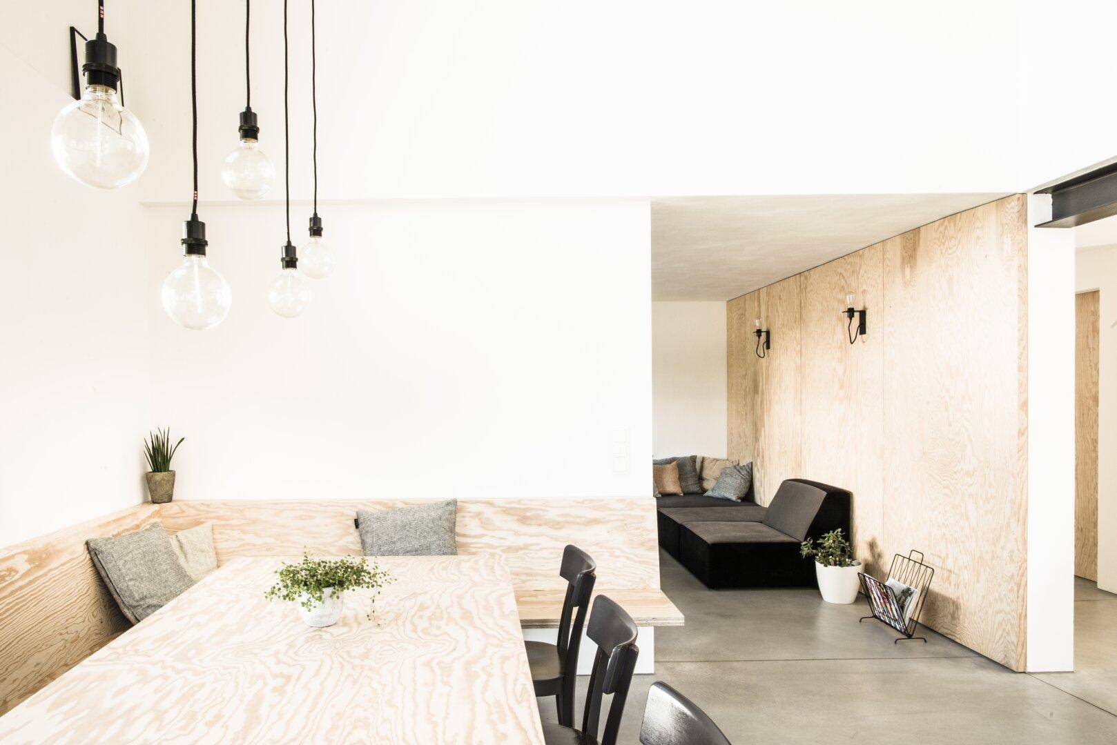Heller Essbereich mit Holzbänken, modernem Design und Pendelleuchten.