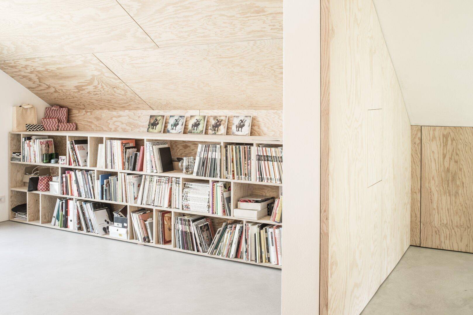 Gemütlicher Bibliotheksbereich mit Bücherregalen, Holzverkleidung und schrägen Decken.