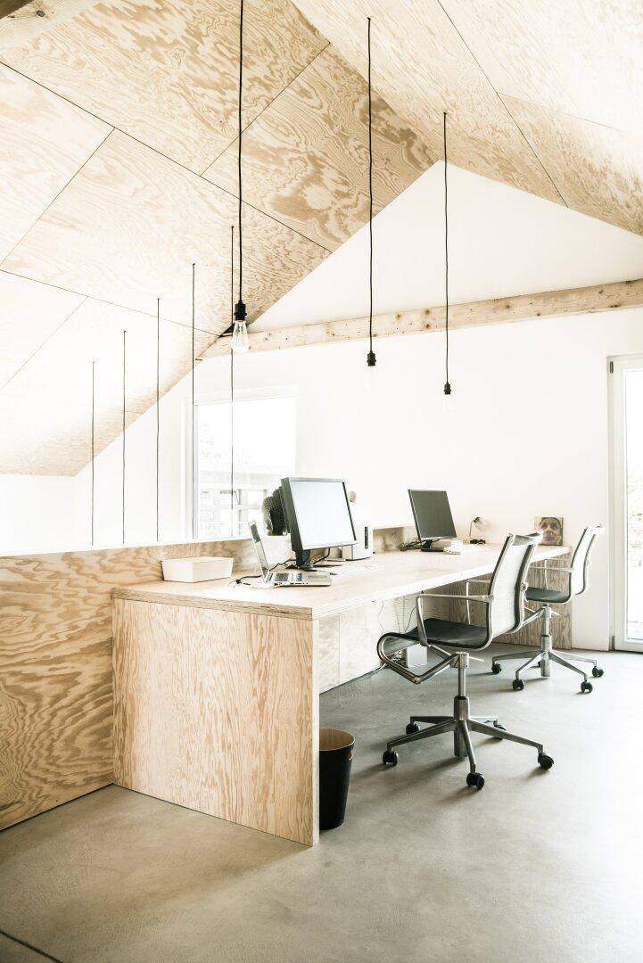 Helles Büro mit schrägen Decken, Holzverkleidung und modernen Arbeitsplätzen.
