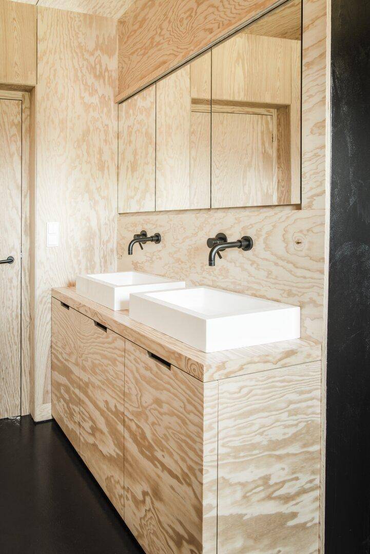 Modernes Badezimmer mit doppelten Aufsatzwaschbecken und Holzverkleidung.