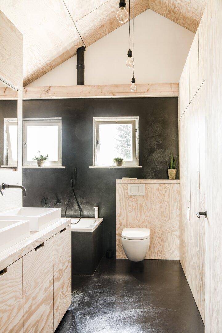Modernes Badezimmer mit Badewanne, Toilette und Holzverkleidung unter schräger Decke.