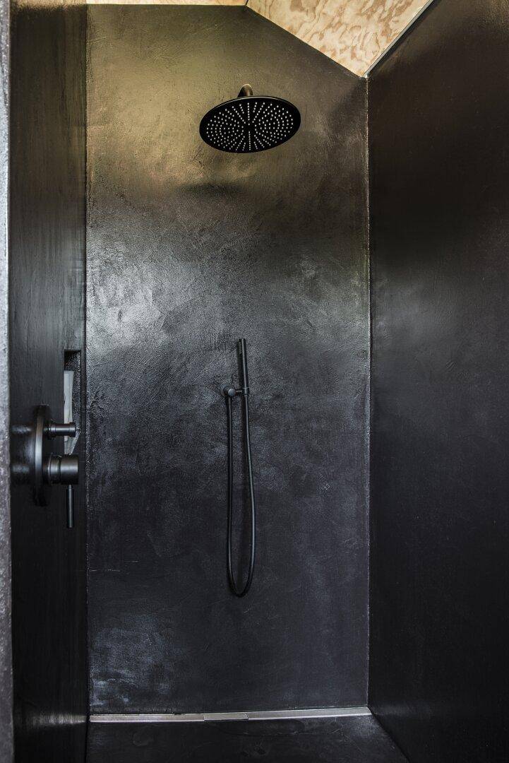 Moderne begehbare Dusche mit schwarzer Oberfläche und Regenduschkopf.