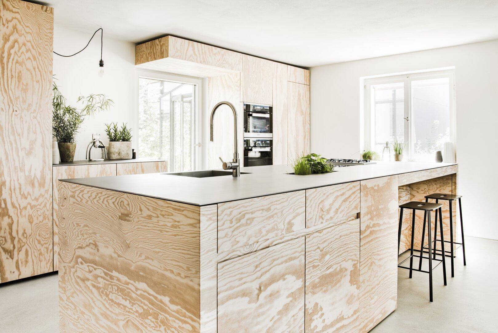 Geräumige Küche mit heller Holzverkleidung, großer Kücheninsel und modernen Armaturen.
