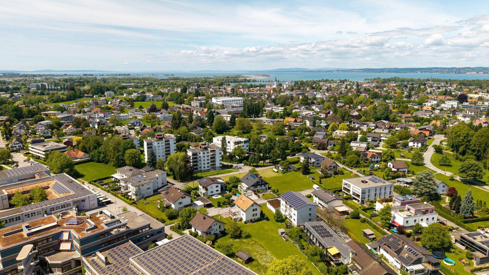 Weitläufige Luftaufnahme einer Wohnsiedlung mit Blick auf den See und die umliegende Landschaft.