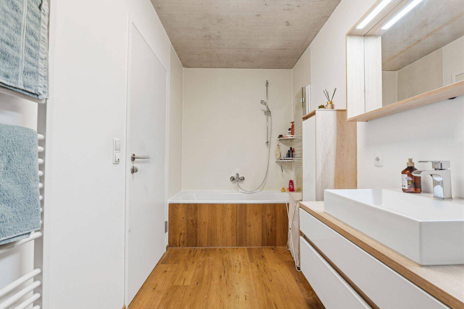 Modernes Badezimmer mit Badewanne, stilvollem Waschbecken und Holzdetails an der Verkleidung.