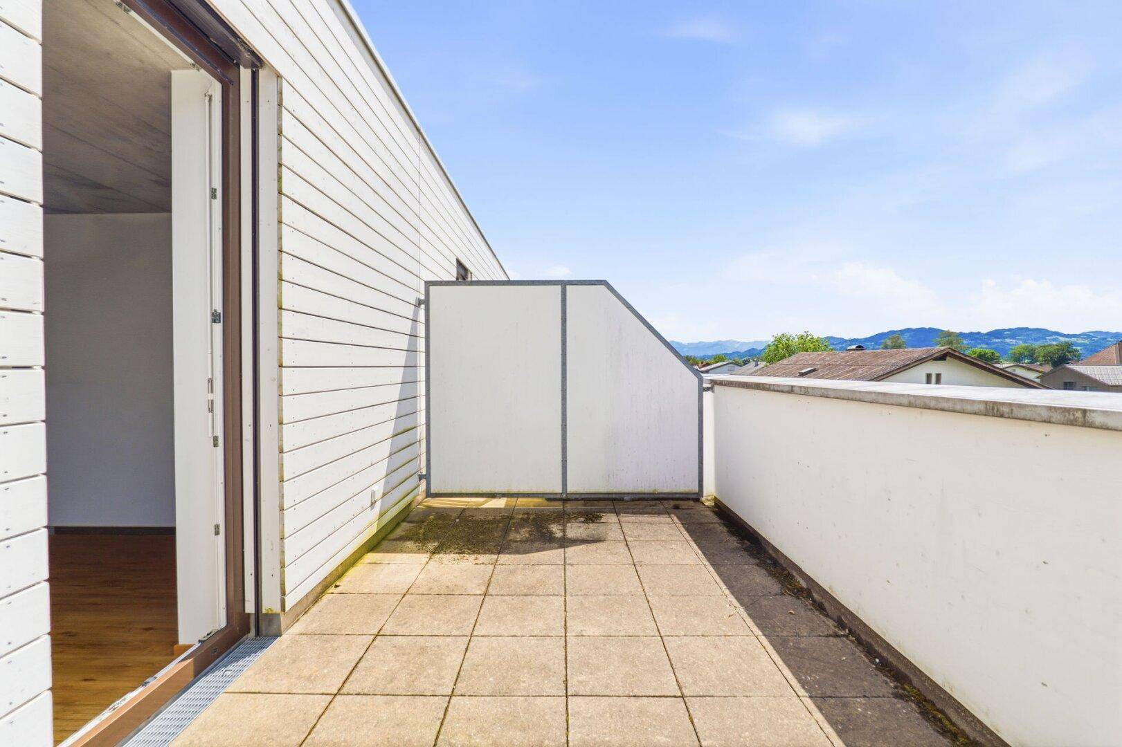 Lange Terrasse mit Fliesenboden und seitlichem Blick auf die Umgebung und die Berge.