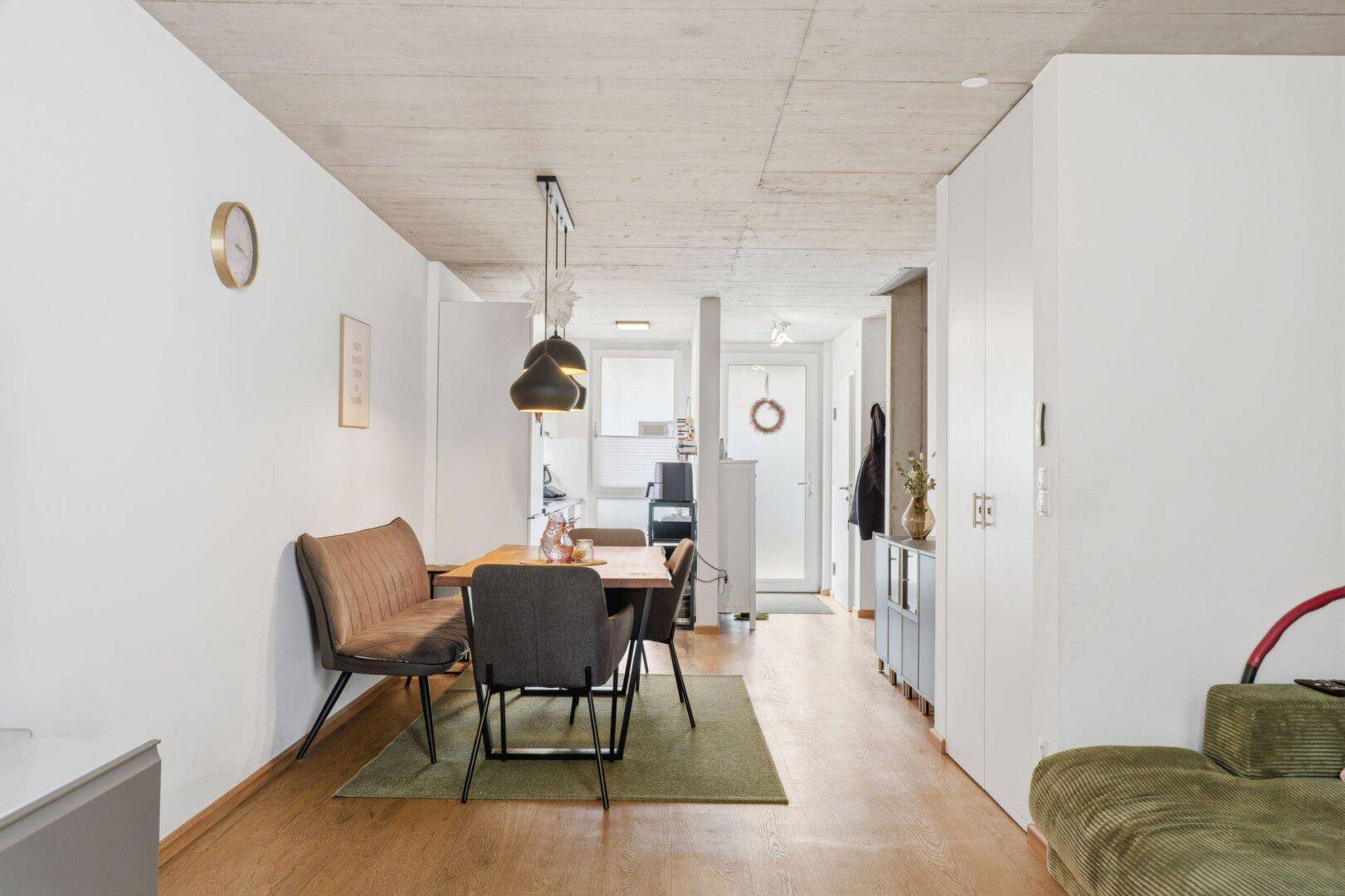 Offener Wohn- und Essbereich mit Holzboden, modernem Esstisch und gemütlichem Sofa.