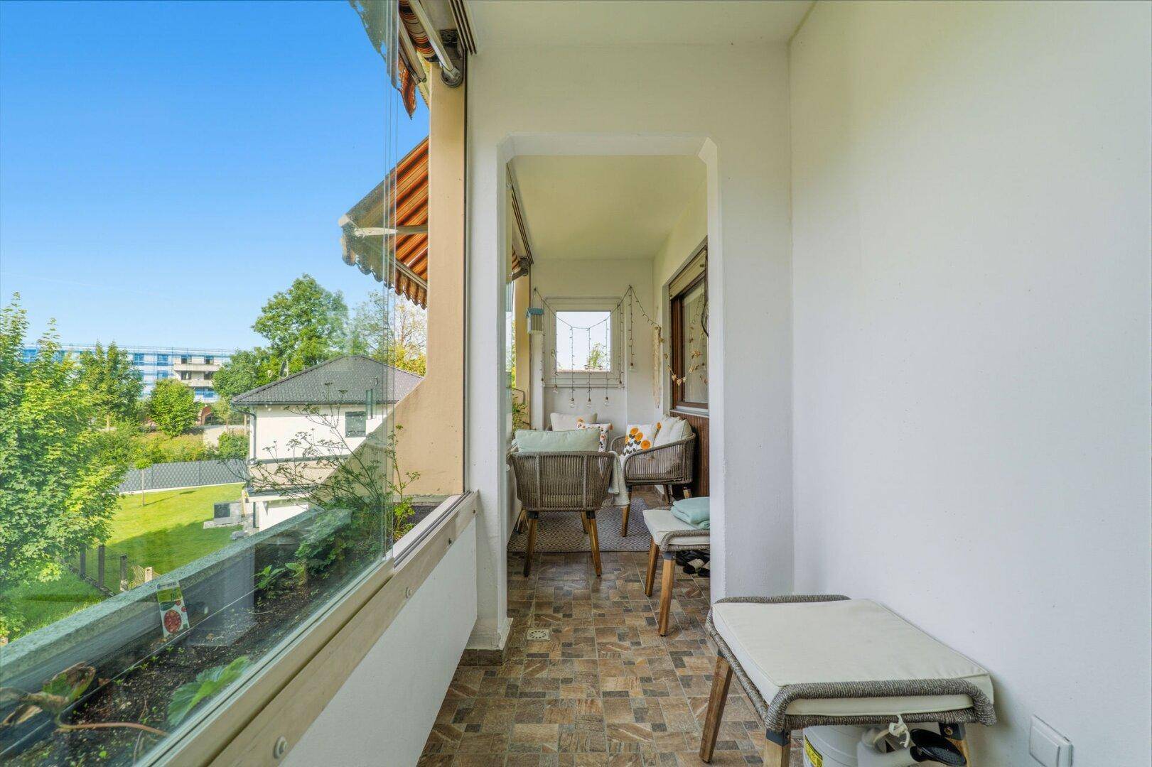 Verglaster Balkon mit Sitzgelegenheiten und Blick ins Grüne, ideal zum Entspannen.