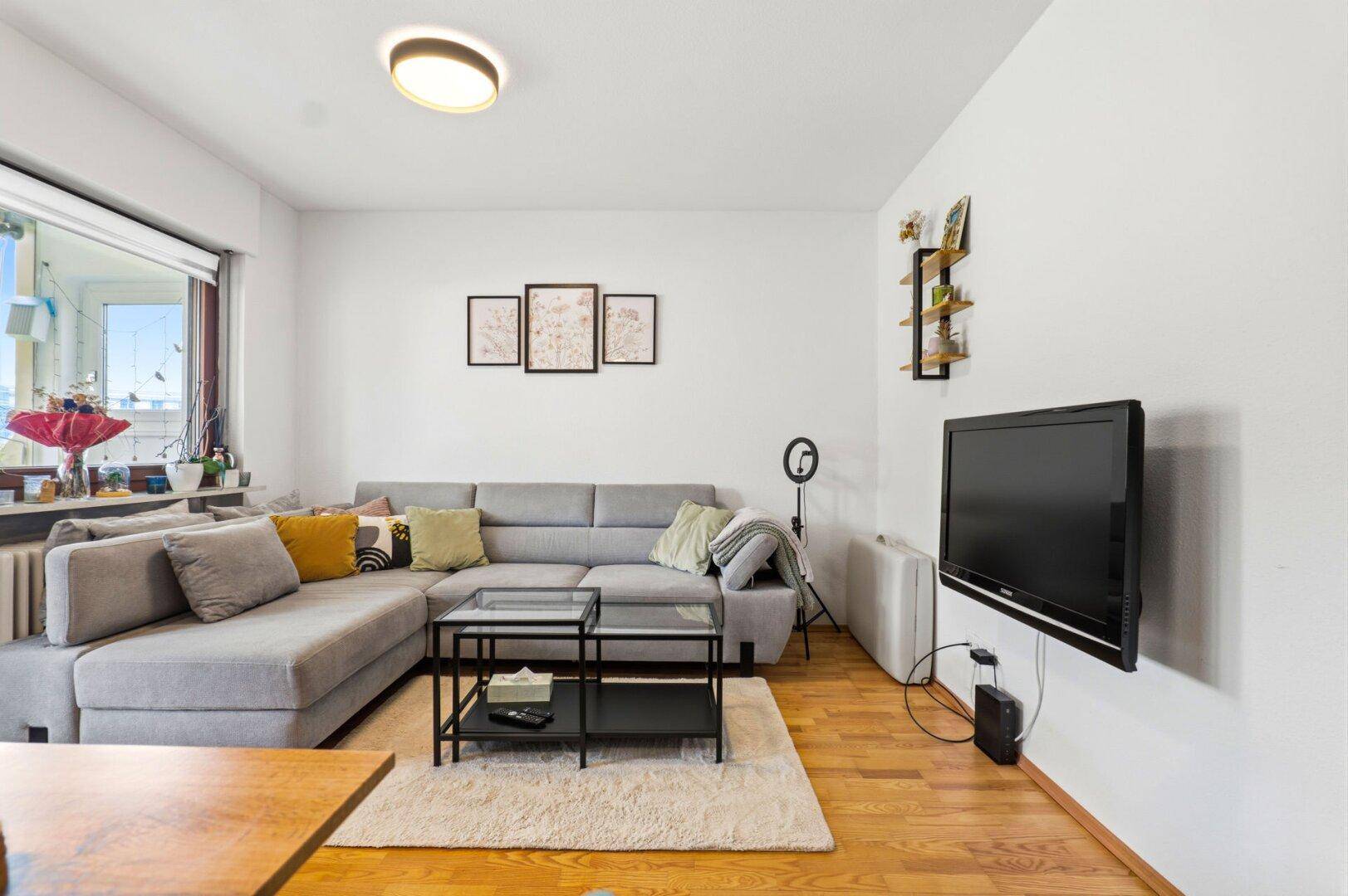 Gemütliches Wohnzimmer mit großem Ecksofa, Holzboden und moderner Einrichtung.