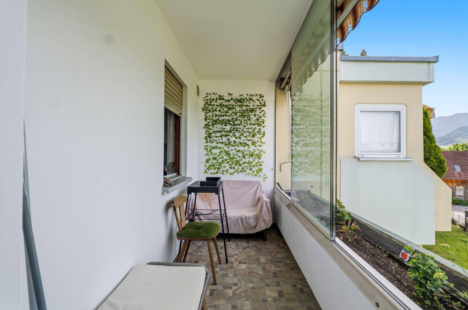 Schmaler Balkon mit Fliesenboden und Blick auf die umliegende Landschaft.