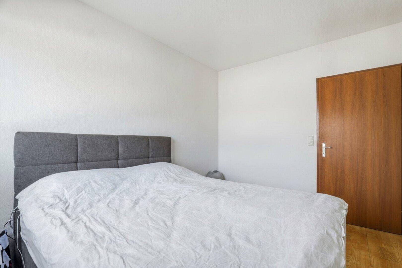 Schlafzimmer mit Doppelbett und Holzboden, schlicht und funktional eingerichtet.
