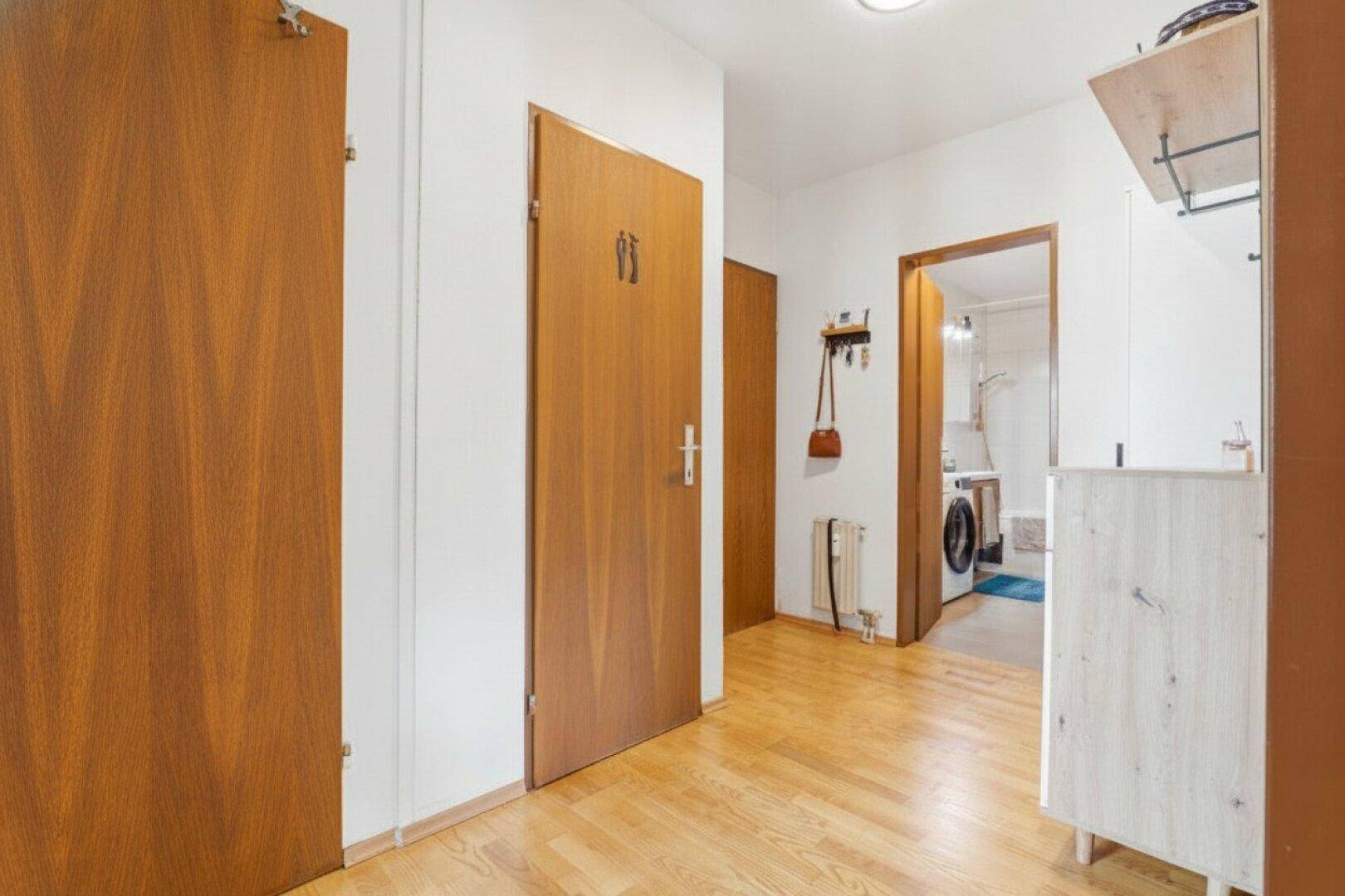 Heller Flur mit Holzboden und Zugang zu verschiedenen Räumen der Wohnung.
