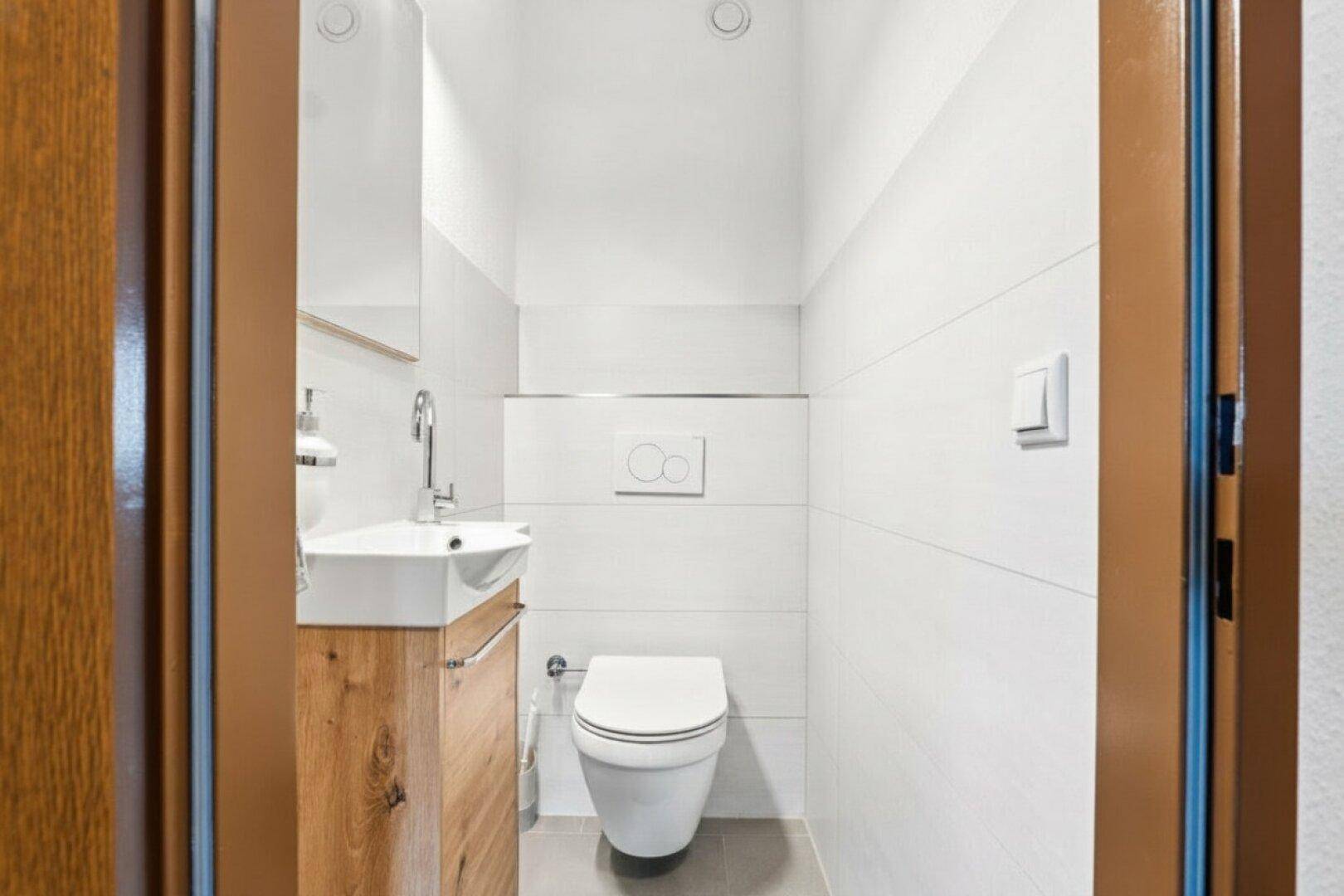 Modernes Gäste-WC mit wandhängendem WC und kleinem Waschbecken.