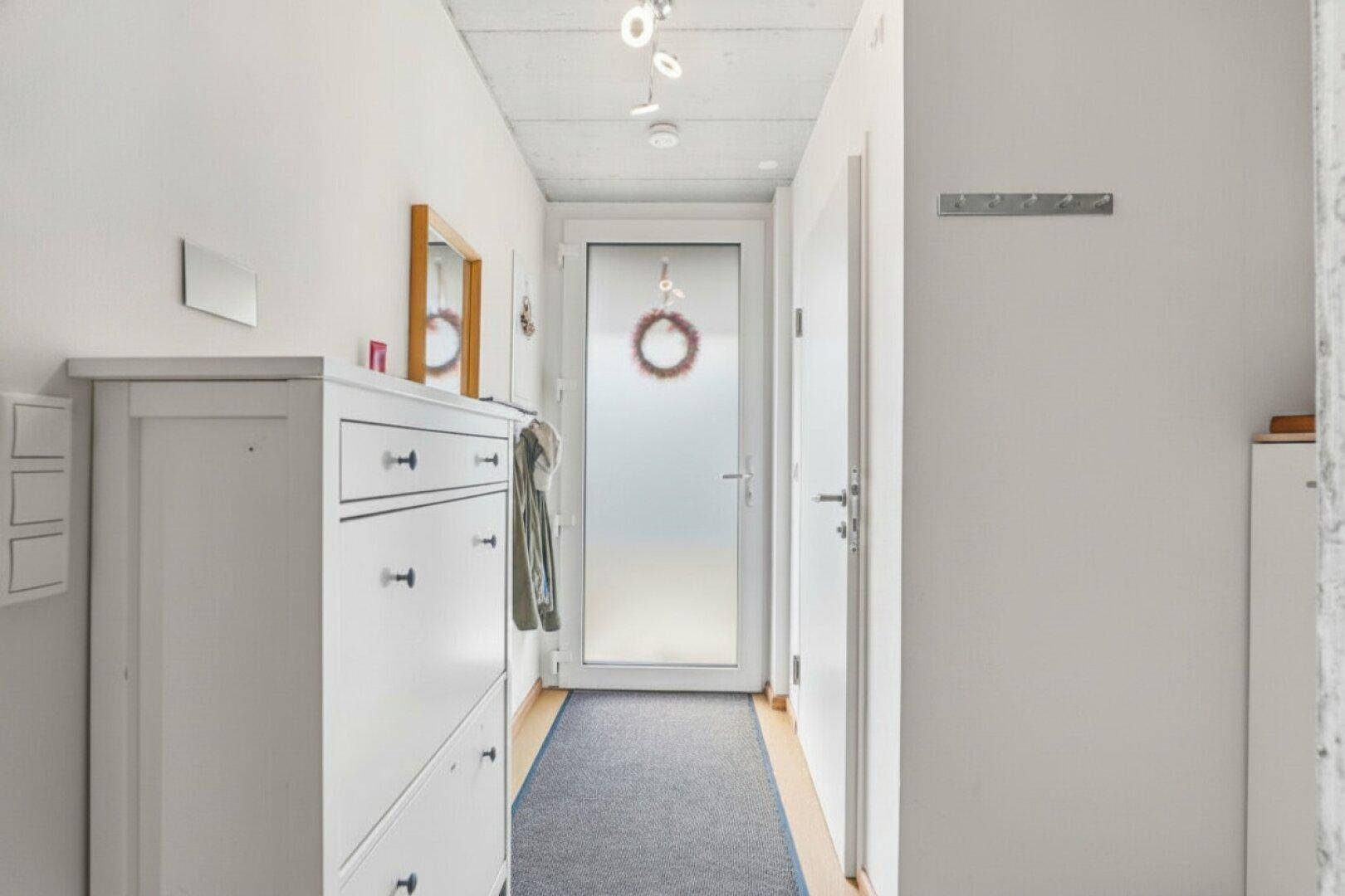 Heller Eingangsbereich mit Schuhschrank und moderner Milchglastür, einladend gestaltet.