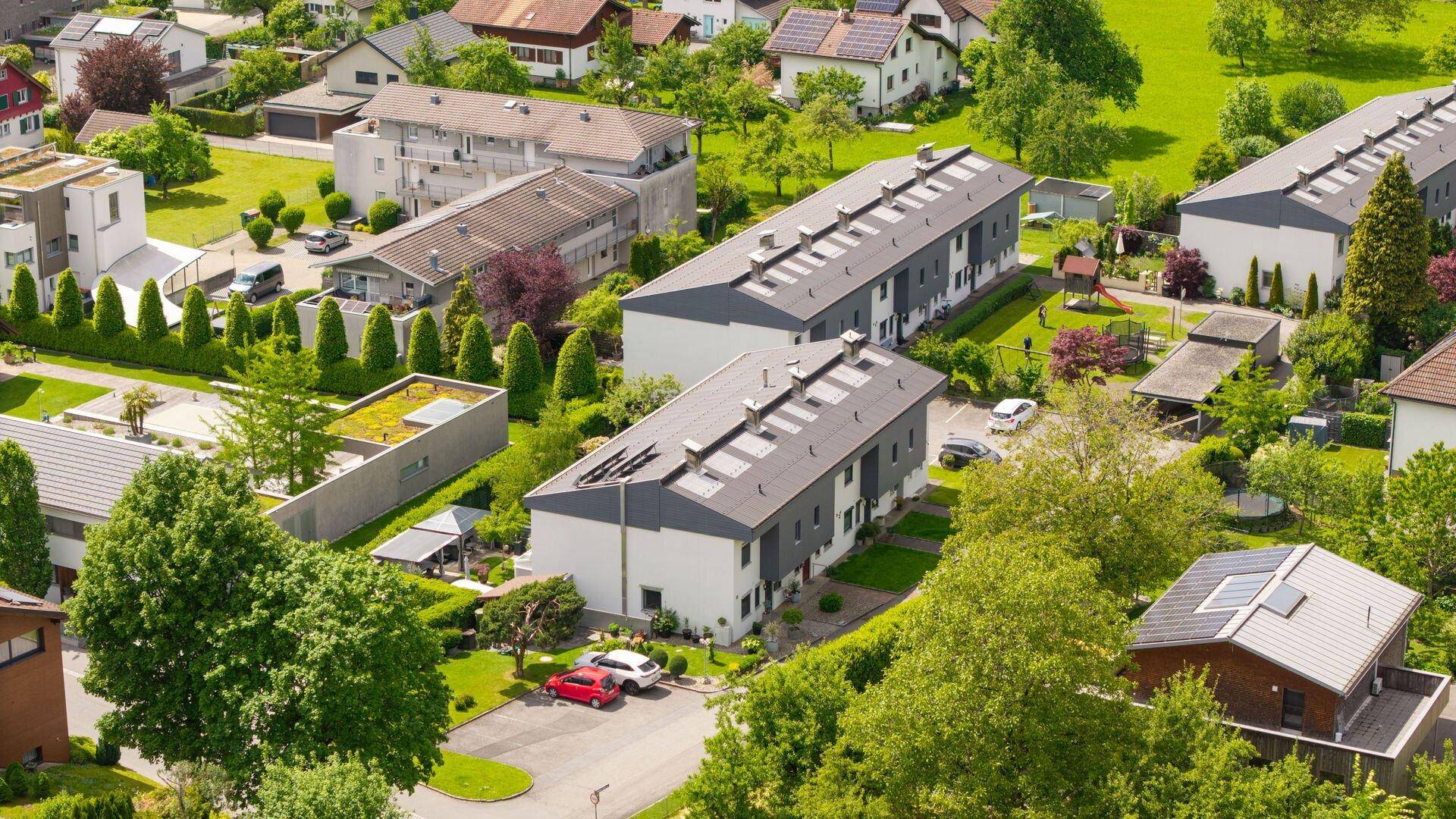 Nahaufnahme einer modernen Wohnsiedlung mit Reihenhäusern, Flachdächern und Photovoltaikanlagen.