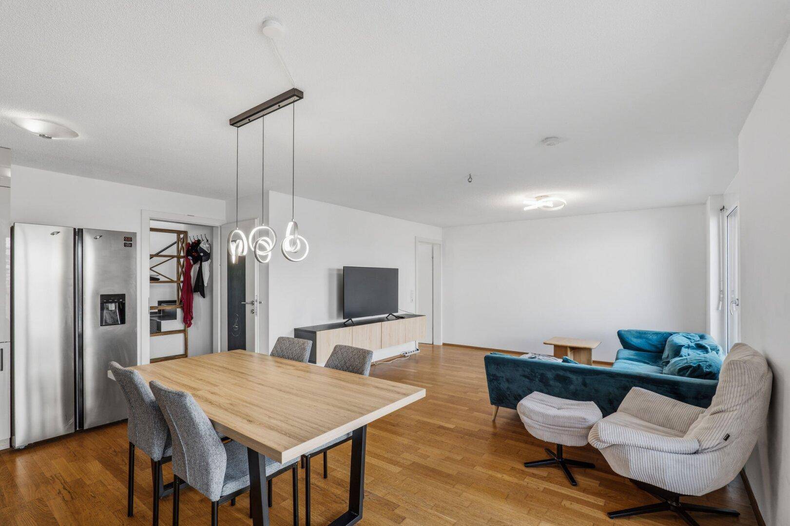 Essbereich mit Holztisch und Stühlen, angrenzend an den Wohnbereich mit Sofa.