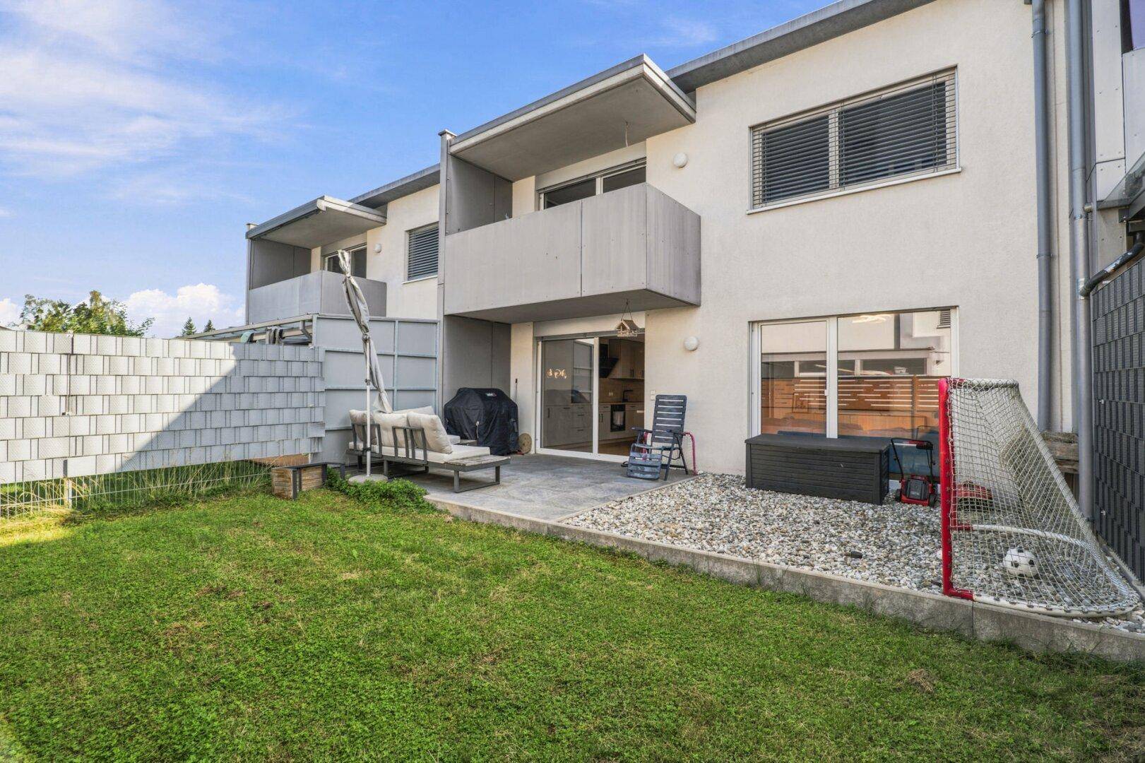 Gepflegter Garten mit Rasenfläche, Terrasse und Spielbereich für Kinder.