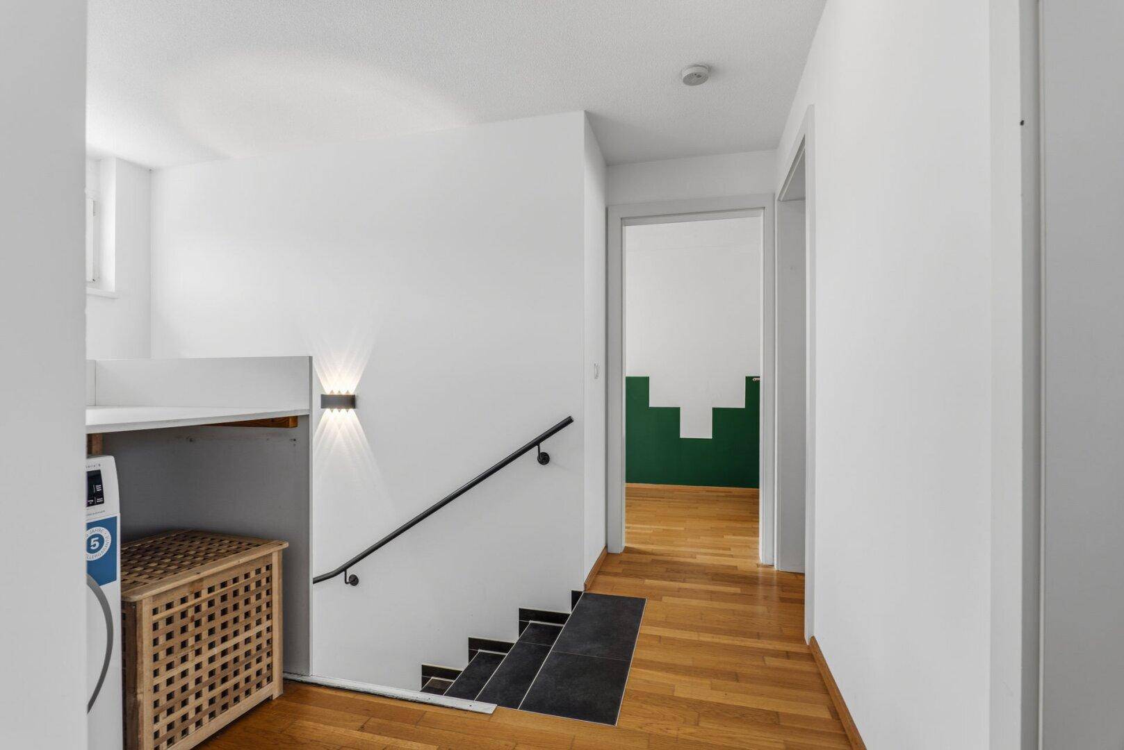 Heller Flur mit Holzboden, Treppe und Zugang zu weiteren Räumen.