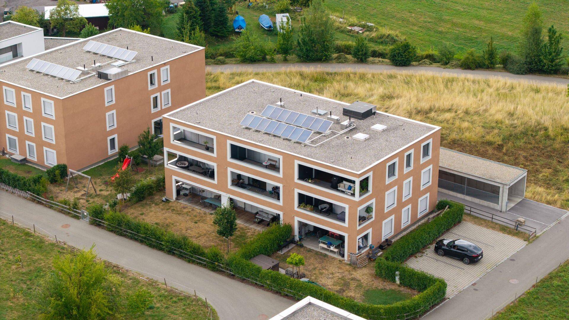 Luftaufnahme von modernen Wohngebäuden mit Flachdächern und Photovoltaikanlagen.