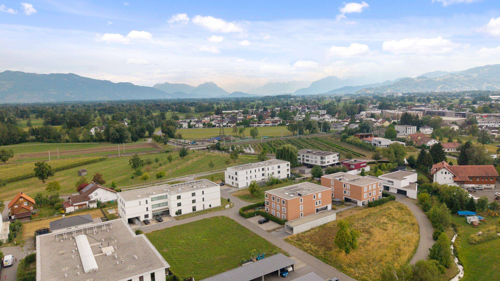 Panoramablick aus der Luft auf die Wohngegend mit Bergen und grüner Landschaft im Hintergrund.