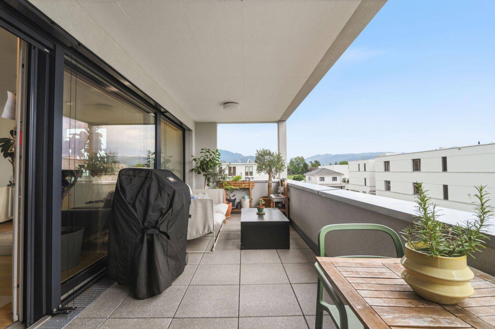 Großer Balkon mit Fliesenboden, Essbereich und weitem Blick auf die Landschaft.